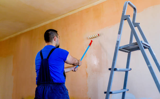 Young male painter painting a wall in a room with a roller