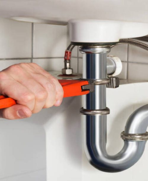 Close-up Of Male Plumber Repairing Sink In Bathroom